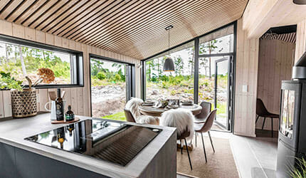 Interiør hytte fra LY Hytta med skråtak og trespiler. Store vinduer. Foto.