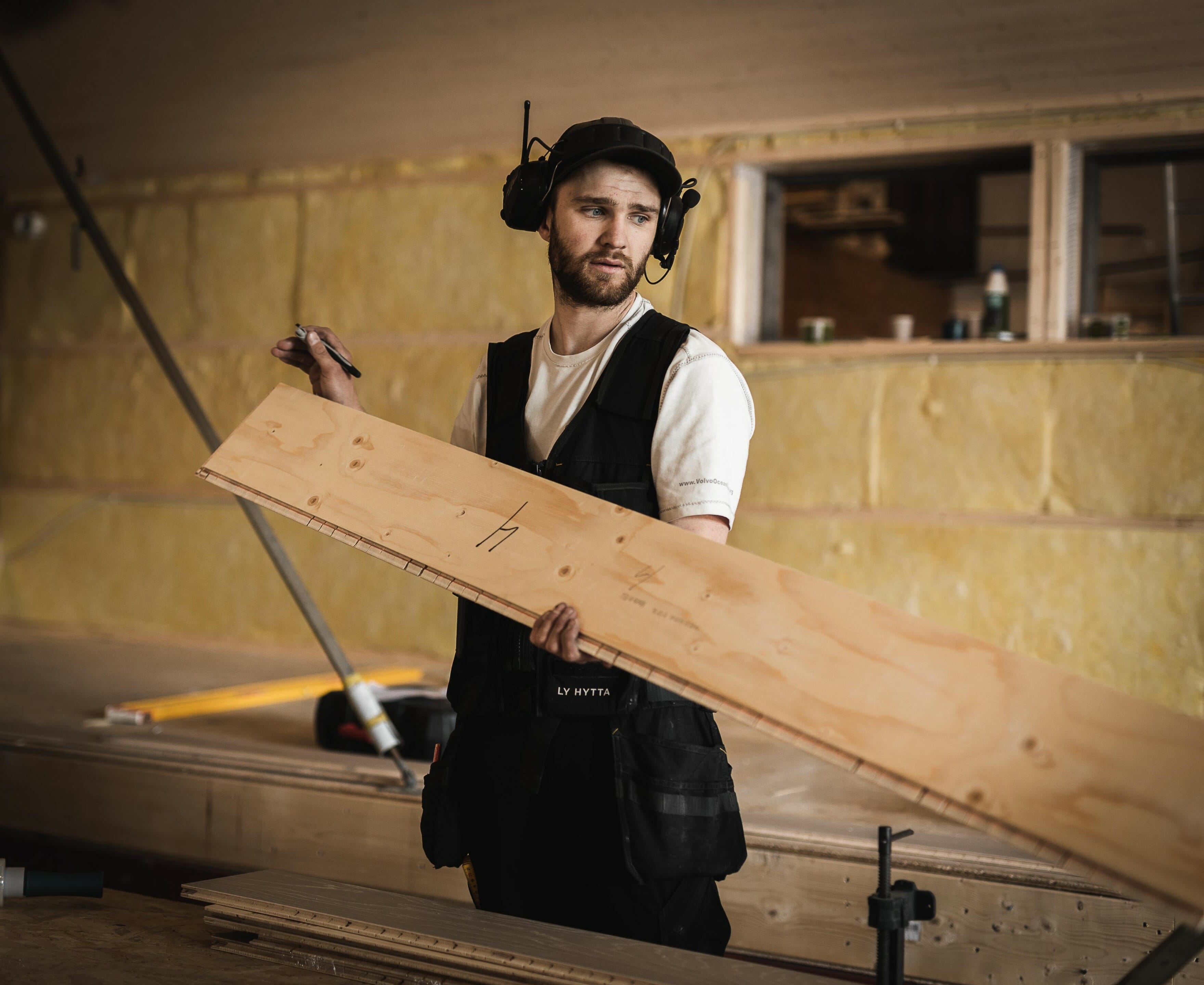 Foto. Mannlig tømrer holder en planke.