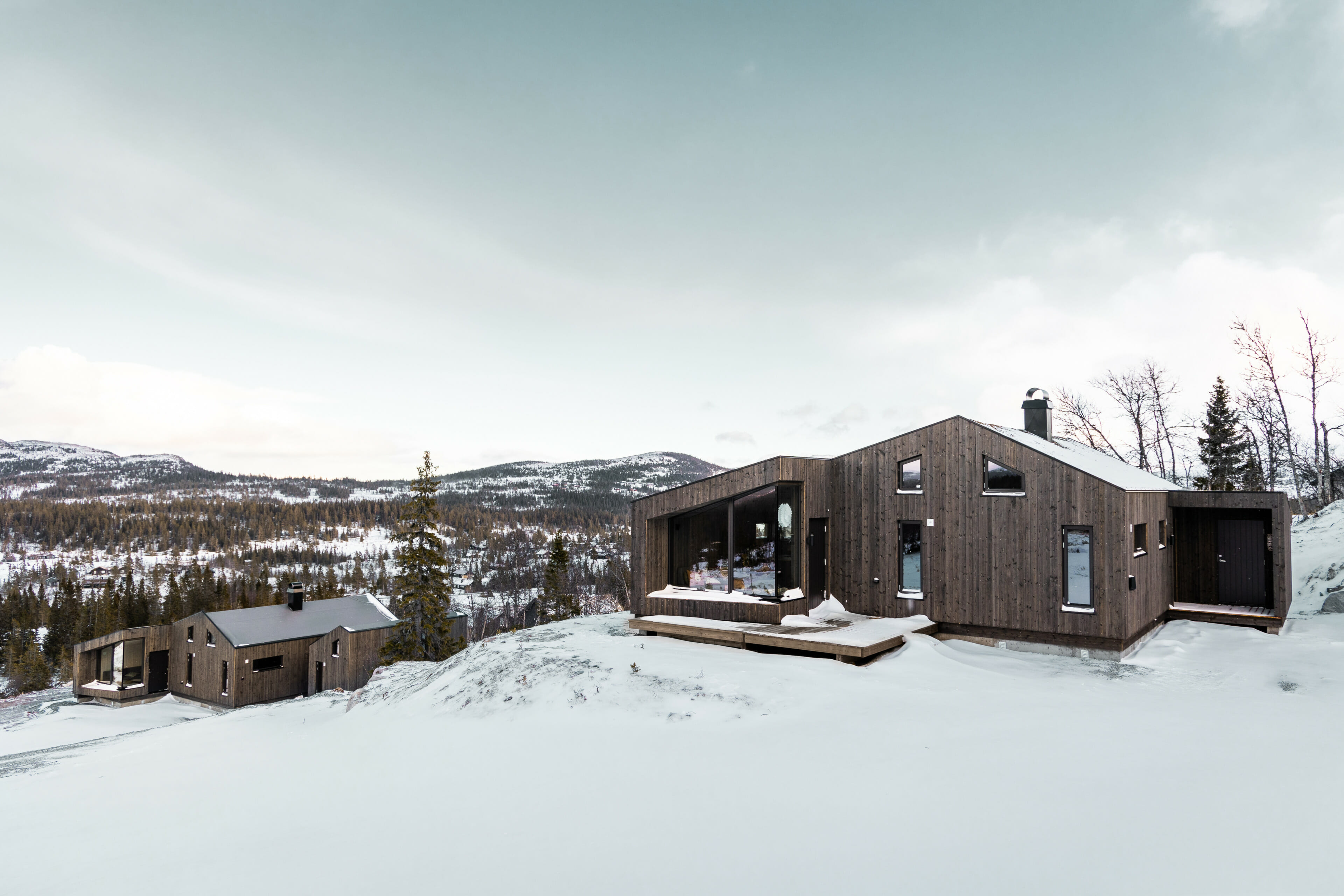 Fjellandskap på Trøgaset med lett snødekke. To moderne brune hytter fra LY Hytta ses i bildet. Foto.