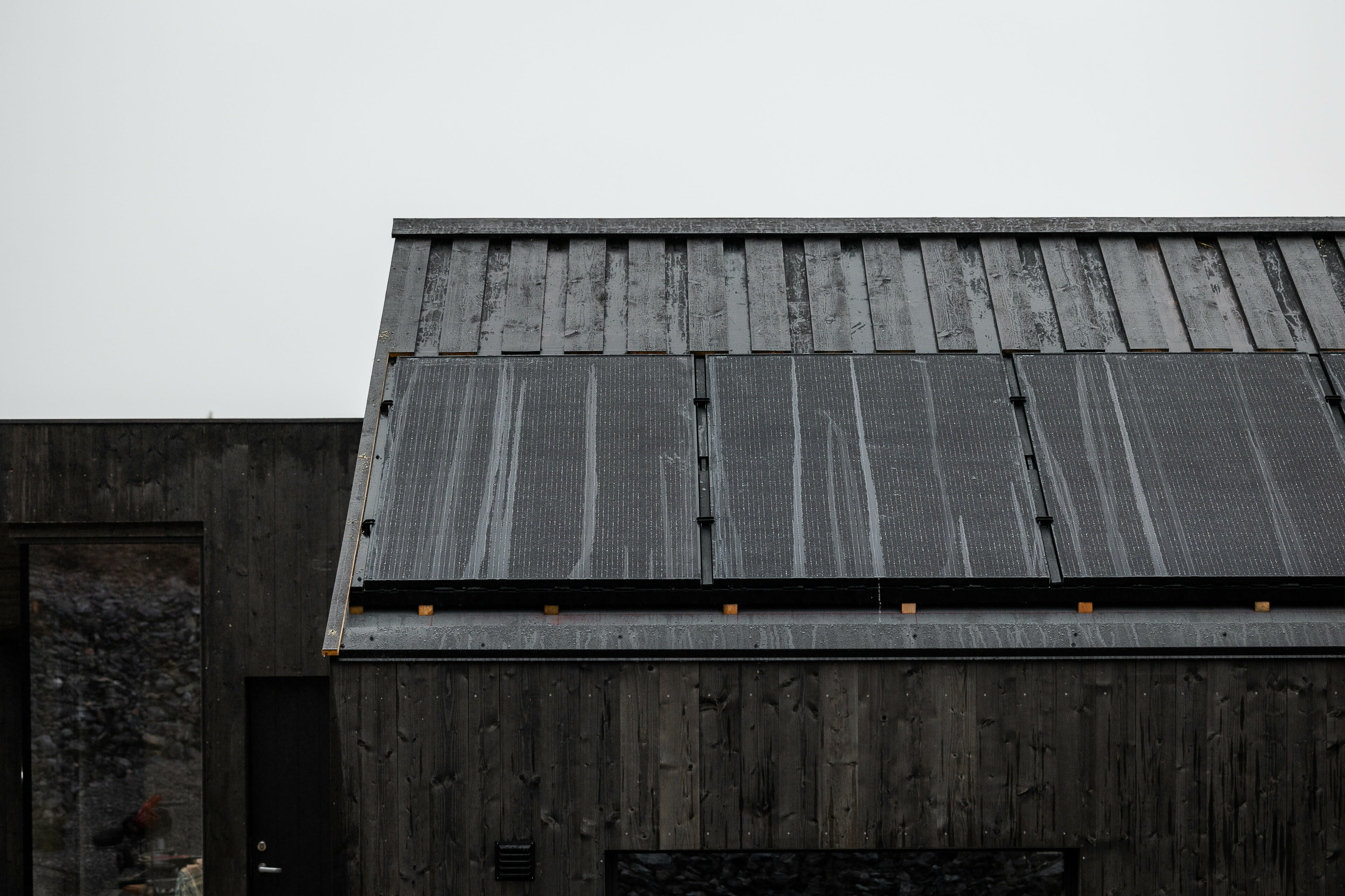 Brunt tretak på moderne hytte. Solcellepaneler på taket. Foto.